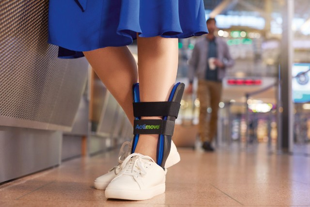 Actimove Talobrace Air Professional Ankle Brace Being Worn At Airport By A Woman Hugging A Man