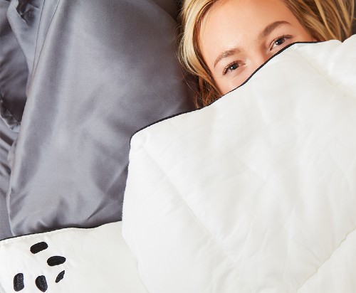 Woman snuggled up in bed with The Cloud Duvet
